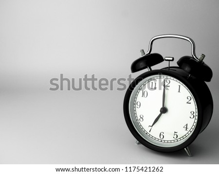 Alarm Clock isolated on white, in black with shadow, showing seven o'clock.