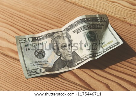 A photo of a USA 20 dollar banknote on a wooden table. This image can be used to represent money. 