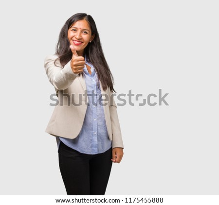 Young business indian woman cheerful and excited, smiling and raising her thumb up, concept of success and approval, ok gesture