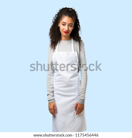 Young girl with apron with sad and depressed expression. Serious gesture on isolated blue background