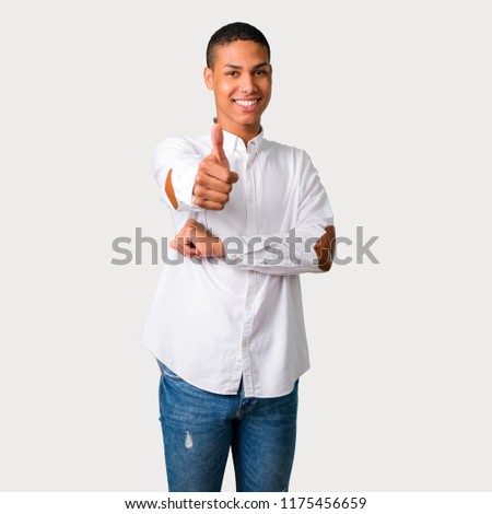 Young african american man giving a thumbs up gesture and smiling because something good has happened on grey background