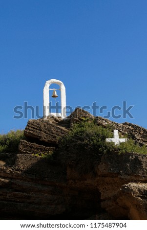 christian cross and bell of a tiny cave church on rocks 