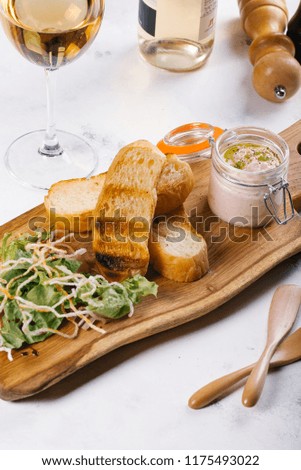 Toasts served with sauce in jar with salad on wooden chopping board