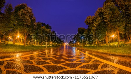 Alley with reflections in Carol Park in Bucharest during rain in a night