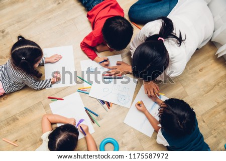 Top view Family happy children group kids boy and girl kindergarten paint drawing on paper with woman teacher education together at interior playroom, back to school concept