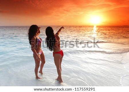 Two beautiful women in bikini enjoying sunset on beach