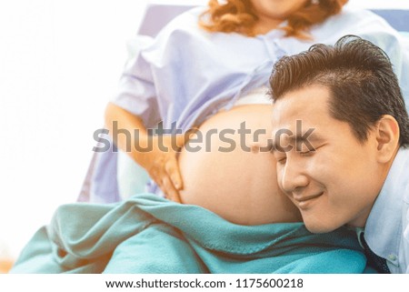 Husband listening newborn through wife belly. Family awaiting for newborn.