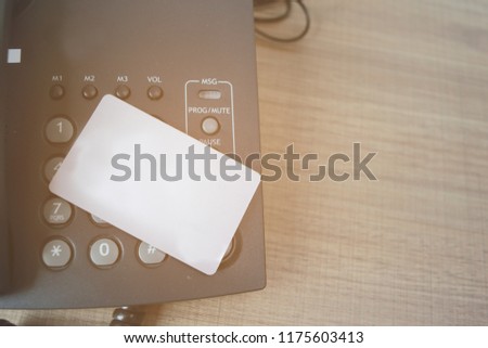 White Credit card and a telephone on table. Concept for business, shopping and finance.Vintage color scheme with orange light.