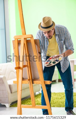 Young male artist working on new painting in his studio