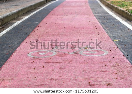 Red bicycle lane on the street with white bicycle icon.