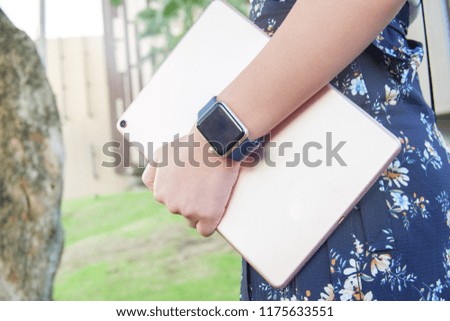 Image of close up business woman walking in park and holding tablet. Wear smart watch in hand.