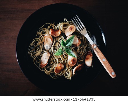 Top view picture of spaghetti spicy sausage on black plate.
