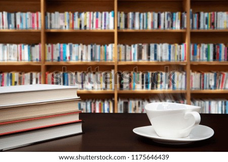 books stacked on the desk with a cup of coffee.