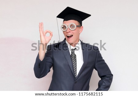 Graduate student is showing Okey gesture sign isolated on gray background. Education concept.