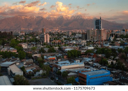 Sunset on snowy Andes mountains of Santiago de Chile with light cloudy sky after rainy day. View from altitude.