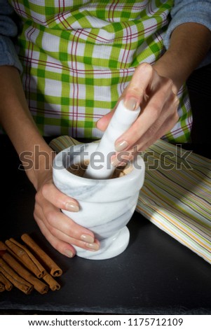 Female hands grind the cinnamon sticks in a mortar