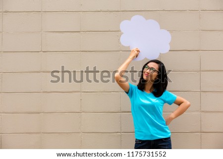 Young woman wearing blue t shirt holding a speech bubble on brick wall background