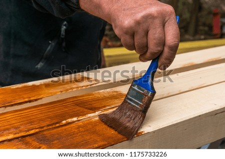Painter with paintbrush painting wooden surface for protection wood from external influences