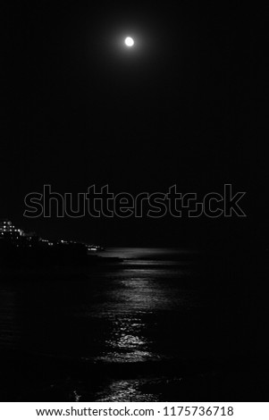 Black and white picture of the moon above the sea