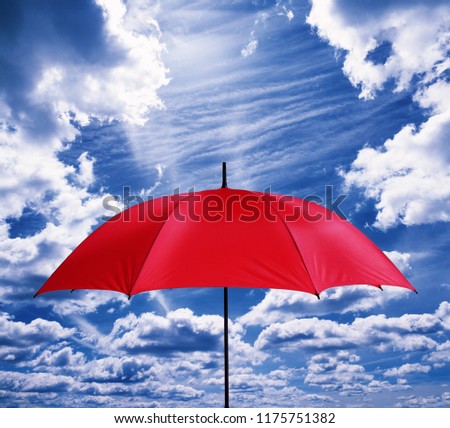 A red umbrella in front of friendly sky with clouds.