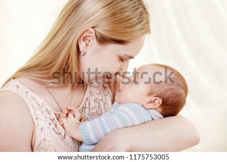Beautiful young mother kissing and hugging her newborn baby boy. Motherhood concept. Happy family concept