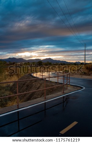 The Loop in Tucson, Arizona. A walking, running and biking path. A beautiful sunset with wet pavement picking up the light and reflecting it. The railing disappears in the distance, nice lines. 2018