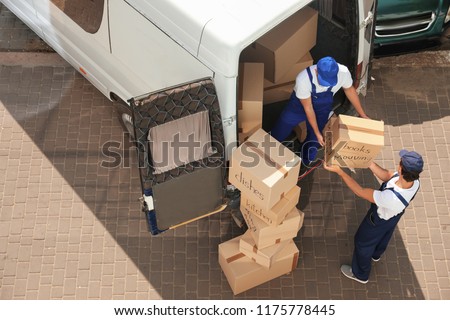 Male movers unloading boxes from van outdoors, above view