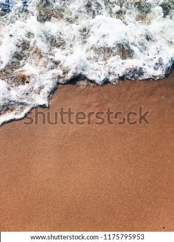 Wave of the sea on sand beach. The wave washes the Golden sand. Foamy waves of the sea roll on the Golden sand.