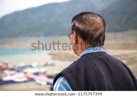 An Indian old Man looking away, Lake and mountain in background