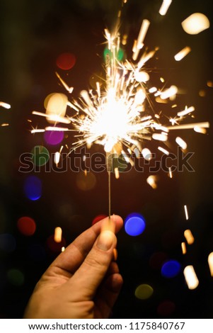 sparkling Bengal fire in his hand on a dark background with a co
