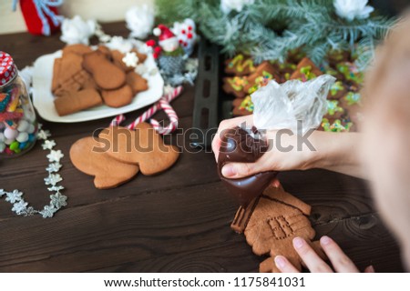 Ginger biscuits in the form are painted with glaze, aysing. Christmas tree branches on a white wooden texture background. The concept of cooking for Christmas and New Year