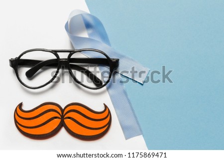Flat composition with sunglasses mustache and blue ribbon on a blue background. 