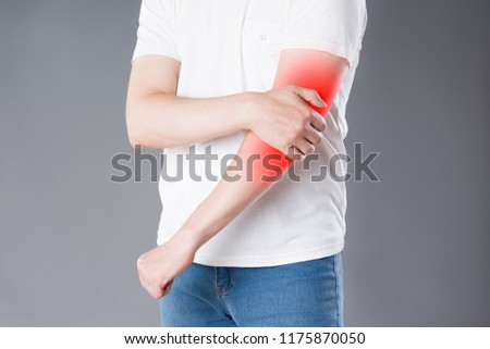 Man suffering from pain in elbow, joint inflammation, painful area highlighted in red
