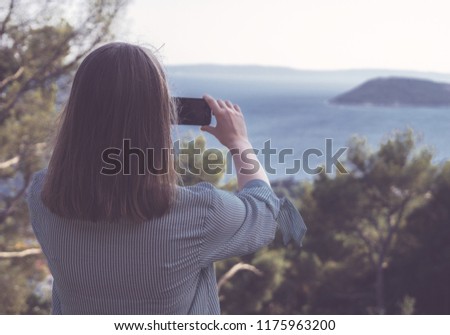 Woman takes pictures of nature by mobile phone.