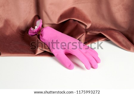 a pink inflated plastic household glove emerging from a pink velvet curtain. Color harmony. Minimal still life color photography