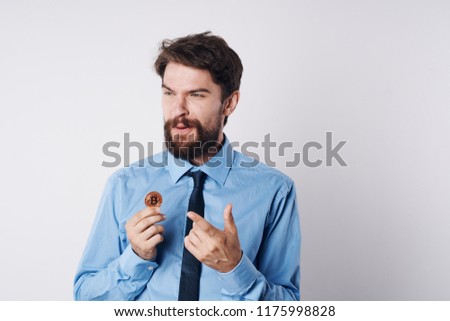 a man in a blue shirt holds a coin in his hand and points with his finger to the side                               