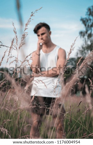 A picture of a man standing in a field with a overthinking body language.