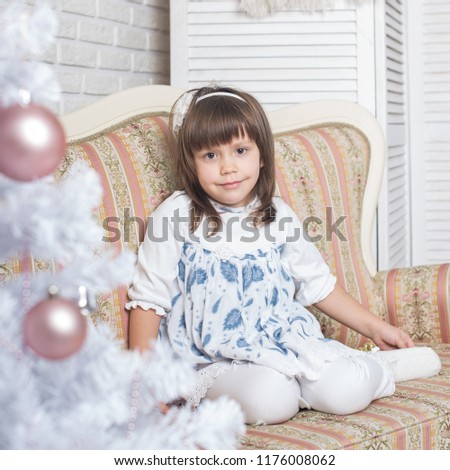 Little cute girl is decorating christmas tree/ Christmas Eve/ Merry Christmas/Happy Holidays
