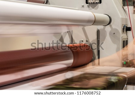 Big printing machine and laminator, armed with red rolls and transparent film. Royalty-Free Stock Photo #1176008752