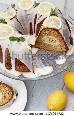Whole lemon cream cheese bundt cake with cream cheese filling in the center and missing slices. Extreme shallow depth of field with selective focus.