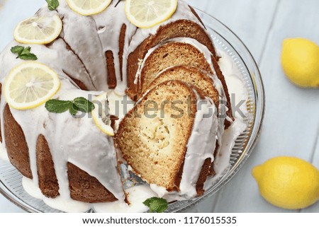 Above shot of lemon cream cheese bundt cake with cream cheese filling in the center cut into slices. Fresh lemons in background. Extreme shallow depth of field.