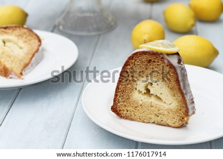Slice of lemon cream cheese bundt cake with cream cheese filling in the center. Extreme shallow depth of field with selective focus on dessert in front of image.