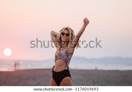 Beautiful young Caucasian woman dancing on beach and looking happy.