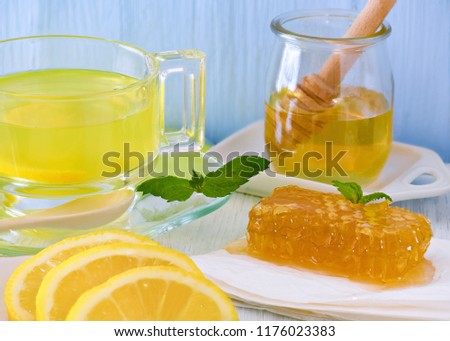 head on close up of honey and lemon hot drink , showing honey-cone  on a blue background room for text 