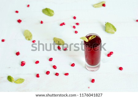 Pomegranate juice with pomegranate seeds and mint leaves on wooden rustic table