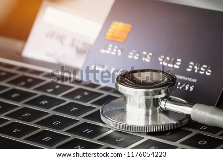 Stethoscope on Mock up Credit Card with number on card at computer in hostpital desk. Health insurance and cost of medical care, self-care during illness using using payments card for medicals service