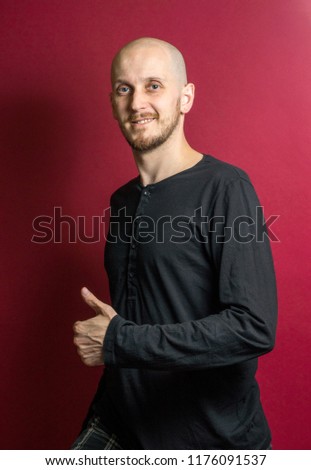 Young white skin man with beard voting and making a thumb up sign against burgundy background