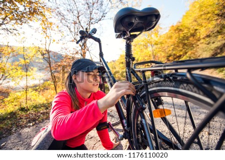 Active sport woman fixing a broken bicycle in the forest