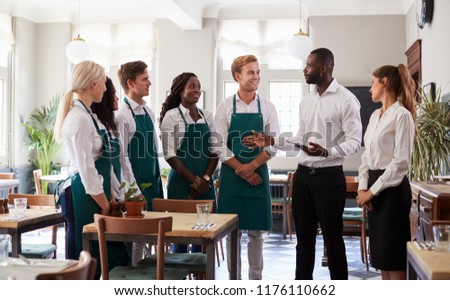 Staff Attending Team Meeting In Empty Dining Room Royalty-Free Stock Photo #1176110662