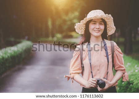Smiling woman traveler with a backpack and enjoy photography, travel girl outdoors. Happy woman with a vacation camera.
